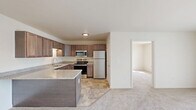 Located at 2040 Taylor Road in Auburn Hills, Michigan, this single-floor residence offers four bedrooms, two bathrooms, and a thoughtfully arranged layout that maximizes every square foot. The open-concept kitchen and living area serves as the heart of the home, featuring rich dark wood cabinetry, granite-style countertops, a central island, and a full suite of stainless steel appliances including a refrigerator, range, microwave, and dishwasher. Stone-tile flooring anchors the kitchen and transitions seamlessly toward the carpeted living area, which is bathed in natural light from a large sliding glass door that opens to an outdoor balcony with views of surrounding greenery. The four bedrooms are finished with plush wall-to-wall carpeting and include ample closet space, with three dedicated closets throughout the unit. The primary bedroom is generously sized and offers comfortable proportions. The two bathrooms are well-appointed, each featuring granite-style countertops, dark wood vanities, and stone-tile flooring that mirrors the kitchen's design aesthetic. A combined bathroom and laundry space adds to the home's functional convenience. Throughout, neutral tones and clean finishes create a bright, move-in-ready atmosphere suited for a variety of lifestyles.
