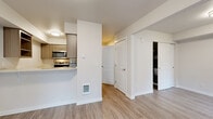 Located at 256 Prince Ave in Bellingham, WA, this efficient one-bedroom, one-bathroom unit offers a well-designed layout across a single floor. Wood-style plank flooring runs throughout the space, providing a clean, cohesive look that ties each room together.

The living area is bright and open, featuring neutral walls and access to an outdoor area through a glass-panel door, allowing natural light to filter in. A built-in wall shelf and desk area add functional storage and workspace options to the living space.

The kitchen is thoughtfully laid out with warm wood-tone cabinetry, light countertops, and stainless steel appliances including a full-size refrigerator, microwave, and dishwasher. A peninsula-style counter connects the kitchen to the living area, making the space feel open and practical.

The bedroom is a comfortable, private retreat with a window offering outdoor views and ample wall space. The bathroom includes a full tub/shower combo with clean white surround, complemented by tile flooring in a neutral stone pattern.

A hallway with multiple door access points connects the rooms efficiently, and the overall design palette of whites and warm neutrals gives the unit a fresh, modern feel throughout.