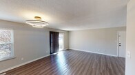 This single-floor residence in Indianapolis, IN, offers a thoughtfully updated interior with a clean, neutral palette throughout. The main living area makes an immediate impression with its rich, dark wood-look luxury vinyl flooring that reflects natural light streaming in through a glass-paneled front door. A contemporary dual-ring LED ceiling fixture with a gold accent adds a modern touch to the space. Neutral gray walls and white trim carry consistently through the home, creating a cohesive and versatile aesthetic. A textured ceiling is present throughout.

The layout flows from the living area down a central hallway connecting the remaining rooms. The kitchen is a standout feature, showcasing white shaker-style cabinetry with matte black hardware, a classic white subway tile backsplash, dark granite-look countertops, a stainless steel double-basin sink, and black appliances including an electric range. The combination is both striking and practical.

The bedrooms feature plush neutral carpeting and windows that bring in natural light, providing comfortable, quiet retreats. Two bathrooms serve the home, each finished with black fixture hardware, tub-shower combinations, and clean white surrounds. One bathroom includes dark countertop detailing consistent with the kitchen's design language. Overall, the space presents a move-in-ready, updated environment with modern appointments throughout.