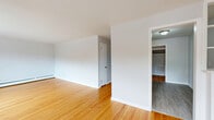 Located at 187 S Allen St in Albany, NY, this 2-bedroom, 1-bathroom unit offers a well-organized single-floor layout. Warm hardwood floors flow throughout the living areas and bedrooms, lending a classic character to the space. The living area is notably bright, featuring multiple windows that invite generous natural light and offer views of the surrounding neighborhood. Baseboard heating runs along the walls, ensuring efficient warmth throughout. The kitchen is outfitted with white shaker-style cabinetry, dark countertops, and stainless steel appliances including a range and refrigerator, complemented by light-toned vinyl plank flooring. The primary bedroom is a comfortable size, featuring a large sliding-door closet and a window with natural light. The second bedroom also includes a window and baseboard heating, making it a versatile space. A connecting hallway ties the rooms together efficiently. The full bathroom features a clean, all-white aesthetic with subway tile surround, a soaking tub, and a toilet. Throughout the unit, neutral gray-white walls provide a fresh, move-in-ready backdrop that suits a variety of décor styles.