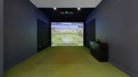 Located at 325 15th St in Jersey City, NJ, this single-floor amenity and entertainment space offers a well-appointed recreational retreat designed for both leisure and social engagement. The layout is thoughtfully divided into distinct activity zones, connected by a hallway that guides visitors through the space.

At the heart of the entertainment area sits a full-sized billiards table with a dark felt surface and a dedicated cue rack, set against crisp white walls with navy blue baseboards and recessed ceiling lighting that ensures excellent visibility for gameplay. Adjacent to the billiards zone, a comfortable lounge area features a tan leather sofa, contemporary armchairs, a round coffee table, and curated wall art, all illuminated by adjustable track lighting that creates a warm, inviting ambiance.

A standout feature is the dedicated indoor golf simulator room, outfitted with a Foresight-powered projection system, a full green turf hitting mat, and dark acoustic wall paneling — offering an immersive, technology-driven experience. The main lounge area also includes a game table with curved seating, a wall-mounted display, and lush potted greenery that adds a touch of life to the modern interior. Throughout, the polished light-toned flooring, clean white walls, and thoughtfully curated furnishings combine to create a cohesive, contemporary atmosphere ideal for recreation and community gathering.