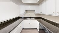 Located at 601 S Peters Rd in Knoxville, Tennessee, this two-story, two-bedroom, two-bathroom home offers a well-organized layout spread across two floors. The main level features a combined kitchen and living area with durable wood-look flooring throughout. The kitchen is equipped with white shaker-style cabinetry, dark granite-style countertops, a tiled backsplash, and stainless steel appliances, including a dishwasher. A pass-through counter connects the kitchen to the adjacent dining area, which receives natural light through a large window. The living room is bright and open, with a carpeted staircase leading to the upper floor. Both bedrooms are carpeted and include ceiling fans with light fixtures and windows with blinds that allow for natural light. The primary bedroom is generously sized and features a walk-in closet with dual hanging rods. Each bathroom mirrors the kitchen's design aesthetic, featuring dark countertops, white cabinetry, and wood-look flooring. One bathroom includes a full tub-shower combination. Hallways on both floors provide practical connectivity between rooms. Textured ceilings are present throughout, and the neutral color palette creates a clean, move-in ready environment.