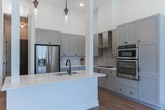 Located at 44 Academy St in the heart of Alpharetta, GA, this well-appointed two-floor home offers a thoughtfully designed interior with consistent, modern finishes throughout. The kitchen is a standout feature, showcasing tall gray shaker-style cabinetry that rises toward soaring ceilings, white quartz countertops, a subway tile backsplash, stainless steel appliances including a French door refrigerator and double wall ovens, a wall-mounted range hood, and a peninsula with an undermount sink — all illuminated by pendant lighting. Warm hardwood-style flooring runs seamlessly through the main living areas, complementing a dining space framed by cool-toned gray walls with generous room for a full-size dining set. The staircase connects both floors with a clean, open layout visible in the 3D floorplan view. Bedrooms offer neutral tones and large windows with blinds, allowing ample natural light. Bathrooms are finished with gray vanity cabinetry, white countertops, large-format tile flooring, and matte black fixtures, with one bathroom featuring a soaking tub and tiled surround. A dedicated laundry closet houses a stacked washer and dryer unit. The primary bath connects directly to a walk-in closet, adding practical convenience to the overall design.