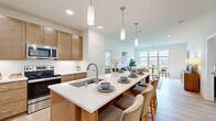 This well-appointed 3-bedroom, 2-bathroom residence in Menomonee Falls, WI offers a thoughtfully designed single-floor layout with a clean, modern aesthetic throughout. Light wood-tone flooring flows seamlessly across every room, creating a cohesive and airy feel.

The open-concept kitchen is a standout feature, showcasing warm wood cabinetry, white quartz countertops, stainless steel appliances, and a generously sized island with seating — ideal for both meal preparation and casual dining. Recessed and pendant lighting illuminate the space with style.

The adjoining living room is bright and welcoming, anchored by large windows that invite natural light and provide pleasant outdoor views, creating a comfortable and open atmosphere for everyday living.

The primary bedroom offers a ceiling fan, a natural light-filled window with blinds, and direct access to a dedicated walk-in closet equipped with wire shelving and hanging rods for organized storage. The en-suite bathroom features a dual-sink vanity with wood cabinetry, white countertops, a walk-in glass shower, and light tile flooring. The second full bathroom mirrors the same refined finishes, including a wood vanity and a full tub-shower combination. Each bedroom is comfortable and well-proportioned, continuing the home's consistent warm, neutral palette.