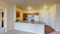 This well-designed 2-bedroom, 2-bathroom single-floor residence offers a functional and comfortable layout suited for everyday living. The kitchen is a standout feature, boasting warm medium-toned wood cabinetry, a full suite of white appliances including a refrigerator, electric range, and built-in microwave, and a generous peninsula with a grey countertop that doubles as a breakfast bar. Wood-style flooring grounds the kitchen, creating a clean contrast with the plush carpeting that flows throughout the living and bedroom areas.

The open living space is expansive and bright, bathed in natural light and offering sliding door access to an outdoor area framed by vertical blinds. Two well-proportioned bedrooms continue the soft, neutral palette with carpeted floors and large windows that invite natural light. One bedroom also features direct outdoor access via a sliding glass door.

Each bathroom is thoughtfully appointed. The first features wood-style flooring, a single-sink vanity with wood cabinetry, and a dedicated shower area. The second includes a full soaking tub with a shower, a toilet, and clean white finishes. Additional storage is provided by a spacious walk-in closet outfitted with multi-tiered wire shelving. Throughout, warm yellow-toned walls and consistent finishes create a cohesive, inviting atmosphere.