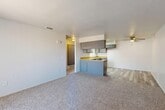 Located at 800 S Norma St in Ridgecrest, California, this single-floor, one-bedroom, one-bathroom unit offers a practical and well-organized layout. The open-concept main area seamlessly integrates the living room, dining space, and kitchen, creating a cohesive and functional zone. The kitchen is equipped with gray cabinetry, warm wood-tone countertops, a gas range, dishwasher, and a peninsula that provides additional prep space and separates the kitchen from the living area. Light wood-style flooring runs through the kitchen, while plush carpet covers the living and dining areas. A ceiling fan overhead aids in climate comfort throughout the main space. The bedroom is a comfortably sized, carpeted room featuring a window with vertical blinds that allows for natural light, along with a dedicated closet for storage. The bathroom includes a full tub-shower combination with white tile surround and wood-style flooring, maintaining a clean and neutral aesthetic. A hallway connects the main living area to the private rooms. Throughout the unit, the neutral white walls and consistent finishes create a bright, clean atmosphere suited for a range of furnishing styles.