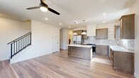 Located at 5758 S Trailside Cir W in Springfield, MO, this well-appointed two-story home offers 3 bedrooms, 3 bathrooms, and generous living space spread evenly across both floors. The main level centers around an open-concept kitchen and living area finished with light-toned hardwood-style flooring and recessed lighting. The kitchen is a standout, featuring warm wood cabinetry in two tones, a textured tile backsplash, stainless steel appliances, a central island with a dark base and white countertop, pendant lighting, and a gold-accented double-basin sink beneath a bright window. A ceiling fan anchors the living area, adding to the comfortable, airy atmosphere. Upstairs, the bedrooms are carpeted and filled with natural light from multiple windows, each room equipped with a ceiling fan. The spacious primary bedroom includes its own ensuite bathroom, which boasts marble-look tile flooring, a double vanity with gold hardware, and a soaking tub with tile surround. Five closets are distributed throughout the home, providing ample storage. A dedicated laundry room and an attached garage with an automatic opener add everyday convenience. The clean, neutral palette and modern finishes throughout give this home a fresh, move-in-ready appeal.