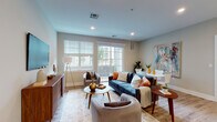 This single-floor residence at 44 Veterans Memorial Drive in Somerville, New Jersey, presents a thoughtfully designed living space with contemporary finishes and a cohesive modern aesthetic throughout. The open-concept living area is a central highlight, featuring light-toned hardwood flooring, recessed lighting, and large windows dressed with clean white blinds that invite abundant natural light. The living room offers generous space for seating arrangements, with direct access to a private outdoor area through a glass door, providing pleasant exterior views.

The kitchen is well-equipped with dark espresso cabinetry, stainless steel appliances, a white quartz countertop, and a peninsula breakfast bar illuminated by pendant lighting — ideal for casual dining and entertaining. The bedrooms are calm and bright, each benefiting from natural light through well-positioned windows, with the primary bedroom offering ample room for a full furniture arrangement.

The bathrooms are finished with tile flooring, dark wood vanities, white quartz countertops, and large mirrors. One bathroom features a tub-shower combination with tiled surround, while another offers a separate shower enclosure. Throughout the residence, a neutral color palette and consistent design language create a polished and welcoming ambiance.