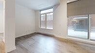 Located at 150 Rue King in Montréal, this well-designed one-bedroom, one-bathroom unit offers a clean, contemporary aesthetic across a single floor. Light-toned hardwood flooring runs throughout, creating a cohesive and airy feel. The welcoming entrance corridor leads past multiple closets, providing ample storage before opening into the main living area.

The open-concept living and dining room is bright and spacious, anchored by large floor-to-ceiling windows that invite natural light and offer views of the surrounding exterior. A wall-mounted mini-split unit ensures year-round climate comfort. The kitchen features white cabinetry, white quartz countertops, stainless steel appliances including a refrigerator, dishwasher, range, and microwave, and is separated from the living area by a practical breakfast bar peninsula.

The bedroom is a comfortable, well-proportioned room with large windows fitted with baseboard heating, light hardwood floors, and a double closet. The bathroom is finished in a crisp all-white palette with large-format floor tiles, a vanity with undermount sink, and a glass-door walk-in shower. The overall design prioritizes clean lines, neutral tones, and functional layout, making this a practical and modern urban residence.