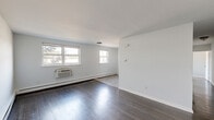 Located at 4100 Longshore Ave in Philadelphia's 19135 zip code, this single-floor, 2-bedroom, 1-bathroom unit offers a practical and well-organized layout. Dark hardwood flooring runs consistently throughout the living areas and bedrooms, providing a cohesive and clean aesthetic against the neutral light gray walls.

The living room is the largest open area of the unit, bathed in natural light from multiple windows and equipped with a wall-unit air conditioner and baseboard heating. It flows directly into the kitchen, which features dark cabinetry, a tile backsplash, stainless steel gas range, and a full-size refrigerator — providing a functional cooking space.

The spacious primary bedroom offers generous proportions, natural light from large windows, and baseboard heating. The second bedroom, while more compact, includes a window with outdoor views and its own baseboard heater. Both bedrooms connect via a central hallway, which also provides access to the bathroom. The bathroom is outfitted with a white vanity, toilet, and a mirrored medicine cabinet with overhead lighting.

Notably, the unit includes five closets distributed throughout, offering exceptional storage. The entrance provides a defined transition into the main living space, completing a straightforward and functional floor plan.