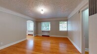 This single-floor space in Portland's Northwest District combines classic architectural character with thoughtful updates throughout. Warm-toned hardwood floors run continuously across the living areas, anchoring the interior with a sense of cohesion and timeless appeal. The main living area is generously proportioned, featuring a textured ceiling, crown molding, and a distinctive arched doorway that adds architectural charm. Multiple windows fitted with blinds allow natural light to filter into the space while framing views of the surrounding greenery.

The kitchen has been updated with gray shaker-style cabinetry extending to the ceiling, light countertops, a decorative patterned tile floor, and open shelving for added functionality. A window above the counter provides natural light, and stainless steel appliances complete the practical layout.

The bathroom retains a classic aesthetic with subway tile lining the walls of the tub surround, a traditional hexagonal black-and-white mosaic tile floor, and a window that brings in natural light. Storage is addressed through a spacious walk-in closet equipped with a full-length hanging rod and overhead shelving. An additional room with a closet and built-in shelving unit offers flexible use. The overall ambiance is clean, bright, and well-maintained.