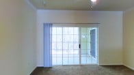 This two-floor residence offers a thoughtfully designed layout that balances comfort and functionality. The interior is finished with classic crown molding that adds an elegant architectural touch to the living areas, while neutral-toned walls and plush carpeting create a warm and inviting atmosphere throughout.

A standout feature of the main living area is the expansive sliding glass door system, which spans much of the exterior wall and floods the space with abundant natural light. Sheer vertical blinds provide privacy while still allowing soft, diffused light to permeate the room. The doors open to a balcony or patio area, offering pleasant views of a lush, wooded landscape — an ideal setting for relaxation and a strong connection to the outdoors.

The ceiling is fitted with a ceiling fan, contributing to both comfort and airflow within the living space. The overall color palette, featuring soft yellows and warm neutrals, lends the home a bright and airy feel.

Spanning two floors, this residence provides ample separation between living and private spaces, with the multi-level layout supporting a functional flow for everyday living. The combination of natural light, outdoor access, classic detailing, and serene wooded surroundings makes this a welcoming and comfortable home.