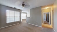 This single-floor residence offers a comfortable and functional layout designed for everyday living. The spacious living area is finished with plush wall-to-wall carpeting, neutral gray walls, and a textured ceiling with a ceiling fan, creating a bright and inviting atmosphere. Large windows fitted with horizontal blinds allow generous natural light to fill the room, while a pass-through connects the living space to the kitchen area.

The galley-style kitchen is well-equipped with stainless steel appliances, including a range, microwave, dishwasher, and refrigerator. White shaker cabinetry lines both walls, complemented by granite-look countertops and a stainless steel sink. Wood-look flooring runs throughout, adding warmth and easy maintenance.

The bathroom features a wide vanity with a stone-patterned countertop, white cabinetry, a large wall mirror with overhead lighting, and a tub-shower combination accented by classic black-and-white tile detailing.

The bedrooms are carpeted and bathed in natural light from well-placed windows. One bedroom benefits from vaulted ceilings, while another offers generous storage with multiple closet options, including a walk-in closet. Throughout the residence, a consistent gray-toned color palette and clean white trim provide a cohesive, move-in-ready aesthetic.