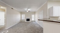 This single-story, 3-bedroom, 2-bathroom home offers a thoughtfully designed layout across a comfortable footprint. The living room serves as the heart of the home, featuring a classic wood-burning fireplace with a white-trimmed surround, crown molding, a ceiling fan with light fixture, and plush carpet underfoot. Natural light filters in through window treatments, creating a warm and inviting atmosphere. The kitchen is equipped with white cabinetry, dark granite-style countertops, a breakfast bar peninsula, white appliances including a range and built-in microwave, and easy-care wood-look flooring that extends throughout the space.

The generously sized primary bedroom includes crown molding, a ceiling fan, plush carpeting, and access to a spacious walk-in closet outfitted with wire shelving for ample storage. The two additional bedrooms are well-proportioned with carpet flooring, ceiling fans, and standard closets with panel doors. The bathrooms are clean and functional, with one featuring a full soaking tub and tile surround with white cabinetry and granite-style countertops. Throughout the home, consistent neutral tones, white trim, and crown molding details lend a cohesive and polished aesthetic.