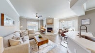 This well-appointed single-floor residence offers a thoughtfully designed open-concept layout that seamlessly connects the living, dining, and kitchen areas. The living room is a standout space, anchored by a corner fireplace framed in white, complemented by crown molding, a ceiling fan, and generous natural light streaming through multiple windows fitted with plantation-style blinds. Warm wood-look flooring runs throughout, adding continuity and a welcoming feel to the home.

The kitchen features white shaker cabinetry, a bold patterned tile backsplash, stainless steel appliances, and a clean white countertop that extends into a breakfast bar. Adjacent to the kitchen, the dining area benefits from large windows that bathe the space in natural light and offer pleasant outdoor views.

The bedroom is a tranquil retreat, complete with a ceiling fan, built-in shelving, crown molding, and a sliding glass door opening to a private balcony. A hallway with distinctive wood-toned wall paneling connects the living spaces to the private quarters.

A secondary living or flex space offers a built-in display niche and direct outdoor access, providing additional versatility. Throughout the residence, the neutral gray-toned walls, consistent flooring, and modern fixtures create a cohesive, contemporary aesthetic with a warm and inviting ambiance.
