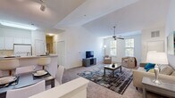 Located at 206 Somerset Bay Dr in Glen Burnie, Maryland, this single-floor residence offers a thoughtfully designed layout that balances openness with functional living spaces. The living room is a standout feature, showcasing soaring vaulted ceilings that amplify the sense of space and volume. A ceiling fan anchors the room, while multiple windows invite abundant natural light and views of the surrounding greenery. Soft carpeting and neutral tones throughout the living areas create a warm, welcoming ambiance.

The kitchen is outfitted with white shaker-style cabinetry, ample counter space, and full appliances including an electric range and refrigerator, all set above durable wood-look flooring. A breakfast bar connects the kitchen to the dining area, making the space well-suited for both everyday meals and entertaining.

Two carpeted bedrooms each feature ceiling fans and generous natural light. The primary bedroom benefits from vaulted ceilings and includes an en-suite bathroom with a wide vanity, white cabinetry, tile flooring, and a separate shower area. A second full bathroom offers a tub-shower combination. Closet storage is present throughout, contributing to the overall practicality of this well-lit, cohesive residence.