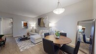 This single-floor residence offers a thoughtfully designed layout that balances comfort and functionality across its key living spaces. The open-concept living and dining area serves as the heart of the home, featuring light hardwood-style flooring, neutral gray walls, and a chevron-patterned area rug that adds texture underfoot. A sectional sofa anchors the living space beneath a bold abstract canvas, while a pendant light fixture illuminates the adjacent dining area, where a round wood table and quilted black chairs create an inviting setting for meals.

The kitchen is well-equipped with rich warm-toned cabinetry, granite countertops, and a full suite of stainless steel appliances, including a refrigerator, range, and microwave. The space is efficiently arranged for ease of use.

Both bedrooms are carpeted and offer natural light through blinds-fitted windows, with ceiling fans providing comfort. One bedroom features two twin beds and a wall-mounted television, along with a walk-in closet, while the other accommodates a queen bed and a dresser. Each bedroom has access to a full bathroom, both finished with warm wood vanities, white countertops, large mirrors, and tile flooring—one with a tub/shower combination and the other with a shower.