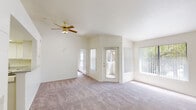 This single-floor residence offers a thoughtfully designed layout that balances open living with functional private spaces. The spacious living room is a highlight, featuring soaring vaulted ceilings, plush carpeting, and a ceiling fan with light fixture. Large windows and a glass-paneled exterior door flood the room with natural light and provide views of surrounding greenery. A pass-through bar connects the living area to the kitchen, which is equipped with white cabinetry, speckled granite-style countertops, a double-basin sink, and a white range, creating a clean and efficient workspace.

The entryway transitions from wood-look flooring into the carpeted main living areas, providing a practical and welcoming threshold. The bedrooms are generously sized, each featuring plush carpeting, vaulted ceilings, and access to natural light. One bedroom includes a mirrored sliding-door closet with built-in shelving, offering excellent storage capacity.

Two full bathrooms serve the residence, each featuring white tile tub/shower combinations with chrome fixtures, wood-look flooring, and speckled countertop vanities. The overall palette throughout the home is light and neutral, with white walls and trim that enhance the airy, open ambiance of the space.
