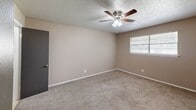 Located at 7125 S Santa Fe Ave in Oklahoma City, OK, this single-floor, one-bedroom, one-bathroom unit offers a practical and well-organized layout. The kitchen features dark-stained cabinetry extending to the upper walls for ample storage, white appliances including a full-size refrigerator and electric range, a double-basin sink, and light ceramic tile flooring. The U-shaped configuration makes efficient use of the space, keeping everything within easy reach. The bedroom is a generously sized retreat, finished with wall-to-wall carpet and neutral warm-toned walls. A ceiling fan with integrated lighting provides both comfort and illumination, while a window allows natural light to filter in. The room also provides direct access to a utility area housing a water heater, as well as a closet for storage. The bathroom includes a wide vanity with a white countertop, an integrated oval sink, a large mirror, and towel bars, all finished in light, clean tones with tile flooring. A textured ceiling is consistent throughout the unit, adding a classic residential character. The overall layout is straightforward and functional, making efficient use of every square foot in a compact, easy-to-maintain single-level design.