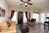 This single-floor residence offers a thoughtfully designed layout that balances comfort and functionality across its living spaces. The living room serves as the heart of the home, featuring wood-style flooring, crown molding, a ceiling fan, and multiple windows dressed in rich drapery that invite abundant natural light. French doors at one end open to the exterior, enhancing the room's airy feel.

The kitchen is well-equipped with white cabinetry, dark speckled countertops, a double basin stainless steel sink, and white appliances including a range and built-in microwave. Wood-style flooring carries through this space seamlessly. Adjacent to the kitchen, the dining area accommodates a full dining set and features track lighting and crown molding detail.

The bedrooms offer plush carpeting, natural light from sizable windows, and direct access to bathrooms. One bedroom connects to an en-suite bath with white vanity cabinetry and dark countertops. The bathrooms feature tub-shower combinations with decorative tile accents, wood-style flooring, and generous vanity storage. The overall ambiance throughout is warm and inviting, with neutral tones creating a cohesive aesthetic.