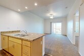 Located at 34232 County Line Rd in Yucaipa, California, this well-appointed one-bedroom, two-bathroom residence offers a thoughtfully designed single-level layout. The open-concept living and kitchen area forms the heart of the home, where warm honey-toned cabinetry, granite-style countertops, and a double-basin sink anchor the kitchen peninsula. Recessed lighting brightens the space, while hardwood-style flooring in the kitchen transitions seamlessly to plush carpeting in the living room. A ceiling fan overhead and sliding glass doors leading to a private balcony enhance airflow and bring in generous natural light, with views of the surrounding neighborhood visible from both the living area and balcony. The spacious primary bedroom features large windows with vertical blinds, plush carpeting, and a comfortable sense of openness. A carpeted hallway connects the bedroom to two bathrooms, one of which includes a vanity with matching cabinetry and granite-style countertop. The bathrooms feature rich wood-look vinyl flooring, adding warmth and durability. A dedicated closet and in-unit laundry area add everyday convenience, rounding out a functional and comfortable living space ideally situated in the Inland Empire region of Southern California.