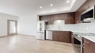 Located at 3111 S St in Sacramento's desirable Curtis Park neighborhood, this one-bedroom, one-bathroom unit offers a thoughtfully designed single-floor layout with a clean, modern aesthetic throughout. The open-concept kitchen and living area serves as the heart of the home, showcasing rich dark-walnut cabinetry that extends to the ceiling, white quartz countertops, a classic subway tile backsplash, and a full suite of stainless steel appliances including a refrigerator, dishwasher, range, and over-the-range microwave. Light wood-toned flooring runs throughout the main living areas, lending warmth and continuity to the space. A bright hallway connects the main living area to the private bedroom, which features plush carpeting, a tray ceiling detail, and dual corner windows that fill the room with natural light. A dedicated closet provides practical storage. The bathroom is finished in the same modern style, with a dark wood vanity, white countertop, large mirror, and a combination tub and shower. Additional hallway space provides functional flow between rooms. The unit's neutral white walls and recessed lighting create a bright, airy atmosphere throughout.