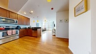 This well-appointed 3-bedroom, 2-bathroom unit is thoughtfully designed to maximize both comfort and functionality across a single floor. The open-concept kitchen and living area serves as the heart of the space, where warm hardwood floors flow seamlessly throughout. The kitchen is outfitted with rich wood cabinetry, dark granite countertops, stainless steel appliances, a peninsula with bar seating, and stylish pendant lighting — ideal for both casual dining and entertaining. The living area is anchored by dramatic floor-to-ceiling windows that frame sweeping urban skyline views and flood the space with natural light. A ceiling fan adds a practical touch overhead. The three bedrooms are carpeted for comfort and each features a sliding mirrored closet, offering functional storage. The primary bedroom provides a quiet retreat with ample space. Both bathrooms are finished with tile flooring, wood vanities, and granite countertops, maintaining a consistent and clean aesthetic throughout. A hallway connects the private and shared spaces efficiently. Overall, the unit strikes a balance between modern urban design and everyday livability, highlighted by its bright, airy atmosphere and city-facing outlook.