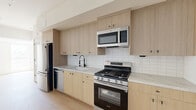 Located at 611 N Virgil Avenue in the heart of Los Angeles, this modern 2-bedroom, 2-bathroom residence offers a thoughtfully designed single-level layout with clean contemporary finishes throughout. Light wood flooring runs continuously across the space, complementing the bright white walls and creating a warm, cohesive aesthetic.

The kitchen is a standout feature, outfitted with flat-front light oak cabinetry extending to the ceiling, marble-look quartz countertops, a white subway tile backsplash, and a full suite of stainless steel appliances including a gas range, dishwasher, built-in microwave, and refrigerator. Matte black hardware adds a modern contrast throughout.

Both bedrooms are bright and airy, benefiting from large windows that invite generous natural light and offer views of the surrounding Los Angeles cityscape. The primary bedroom includes direct access to an en-suite bathroom. Both bathrooms feature a striking design with floor-to-ceiling sage green vertical tile in the glass-enclosed walk-in showers, terrazzo-style flooring, and clean white walls. One bathroom includes a warm wood vanity with matte black hardware, adding an organic touch to the refined palette.

The overall ambiance is modern and minimalist, with a neutral color scheme and quality materials that create a polished, move-in-ready living environment.
