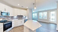 Located at 12400 Dutton Road in Midlothian, VA, this well-appointed single-floor home offers three bedrooms, three full bathrooms, and a thoughtfully designed layout. The open-concept kitchen and living area serves as the heart of the home, showcasing white shaker cabinets, a gray subway tile backsplash, stainless steel appliances, and a large angled island with a quartz countertop. Pendant lighting with gold-toned fixtures adds a modern touch, while hardwood-style flooring and abundant natural light from large windows create a bright, welcoming atmosphere. The living area features a glass-paneled entry door and wide windows that flood the space with daylight. Each bedroom is carpeted and equipped with a ceiling fan, with the secondary bedrooms offering generous proportions and natural light. The spacious primary bedroom includes a well-organized walk-in closet with wire shelving. The bathrooms are finished with white cabinetry, quartz countertops, and wood-look flooring. A dedicated laundry room houses a full-size washer and dryer with overhead wire shelving for additional storage. This home combines clean, contemporary design with practical functionality throughout.