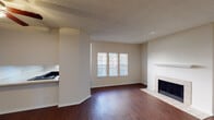 Located at 5330 Bent Tree Forest Dr in Dallas, TX, this single-story residence offers a well-organized layout with a comfortable and functional design throughout. The living area serves as the heart of the home, showcasing rich, dark hardwood-style flooring that extends across the open floor plan. A standout feature is the tile-surround fireplace with a clean white mantel, anchoring the living space and providing a warm focal point. A triple-pane window arrangement allows natural light to fill the room, creating a bright and inviting atmosphere. The kitchen is thoughtfully designed with dark espresso cabinetry, speckled countertops, a double-basin sink, and a window that brings in additional natural light with views of the surrounding greenery. The bedroom is generously sized, finished with plush wall-to-wall carpeting, a ceiling fan with a light fixture, and a window for natural ventilation and light. The bathroom features a wide vanity with speckled countertops, dark cabinetry, a large wall mirror, and bright overhead lighting. Throughout the unit, textured ceilings and neutral wall tones create a cohesive, understated aesthetic that complements a variety of furnishing styles.