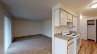 This single-floor residence at 735–751 SE Rivergreen Ave in Corvallis, Oregon offers a functional and well-organized layout designed for comfortable everyday living. The galley-style kitchen is efficiently arranged with white cabinetry, laminate countertops, wood-look flooring, and a full suite of white appliances including a range, refrigerator, and dishwasher. A dedicated pantry with built-in shelving provides generous storage directly off the kitchen. The dining area sits adjacent to the kitchen and is accented by a classic chandelier and a bright window that brings in natural light. The spacious living room features neutral carpet and a sliding glass door fitted with vertical blinds, opening to an outdoor view and filling the space with additional daylight. The transition between the carpeted living area and the wood-look flooring of the dining space creates a natural visual distinction between zones. Bedrooms are carpeted and feature neutral walls, windows with blinds, and closets with bifold doors and hanging rods. The bathrooms include a walk-in shower with a sliding glass door and wood-look flooring, as well as a separate tub-shower combination with clean white surrounds. Throughout the unit, a consistent warm, neutral palette and textured ceilings contribute to a clean and understated aesthetic.