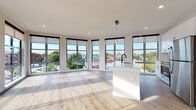 This thoughtfully designed single-floor unit offers a seamless blend of modern aesthetics and functional living. The open-concept living and kitchen area is a true highlight, featuring an expansive array of floor-to-ceiling windows that flood the space with natural light and frame sweeping urban views of the surrounding neighborhood. Light wood-tone flooring runs throughout, complementing the bright, neutral palette of the walls and ceilings.

The kitchen is outfitted with crisp white shaker cabinetry accented by matte black hardware, a classic subway tile backsplash, quartz countertops, and a full suite of stainless steel appliances. A central island with a built-in sink serves as both a functional workspace and a natural gathering point within the open layout.

The bedrooms offer generous proportions, with large windows inviting ample daylight and ceiling fans providing year-round comfort. Each bedroom is accompanied by closet space, including a spacious walk-in closet with wire shelving for organized storage.

The bathrooms are finished with clean, contemporary detailing — featuring white tile surrounds, a sliding glass-enclosed shower, a double-sink vanity with white cabinetry, and matte black fixtures that provide a refined contrast. A second bathroom includes a tiled tub-shower combination. Wood-look flooring carries throughout the bathrooms, maintaining a cohesive design across the entire unit.