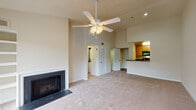 This single-floor residence offers a well-organized layout that balances open communal spaces with private retreats. The living room serves as the central gathering space, highlighted by soaring vaulted ceilings, a ceiling fan with light fixture, and a classic fireplace with a clean surround. Large windows and a sliding glass door flood the room with natural light while offering outdoor views, and plush carpeting adds warmth underfoot. The kitchen is designed for functionality, featuring a galley-style configuration with light wood cabinetry, dark granite-style countertops, hardwood flooring, and black appliances including a refrigerator, range, and dishwasher. A breakfast bar counter connects the kitchen to the living area, creating an open, social feel. The bedrooms are carpeted and well-lit by windows with blinds, offering comfortable, versatile spaces. The bathrooms are straightforward and clean in design; one features a tub-shower combination with tiled surround, while another includes a vanity with warm wood cabinetry and a separate tub-shower area with tile flooring. Overall, the residence presents a bright, neutral palette throughout.