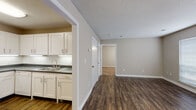 This single-floor unit offers a practical and comfortable layout designed to maximize livability. The interior is unified by rich, dark hardwood-style flooring that runs throughout the main living areas and kitchen, complemented by neutral warm-beige walls and crisp white trim throughout.

The kitchen is well-equipped and efficiently arranged in an L-shaped configuration, featuring white shaker-style cabinetry with brushed nickel hardware, dark countertops, a classic white subway tile backsplash, and a full suite of white appliances including a refrigerator, electric range, and dishwasher. A double-basin sink with under-cabinet lighting adds both function and brightness to the space.

The living area is open and airy, with multiple windows fitted with horizontal blinds that allow for ample natural light. A textured ceiling adds visual character throughout.

The bedrooms are carpeted for comfort, each outfitted with ceiling fans with integrated lighting and windows that invite natural light. Closet access is available within the bedroom spaces.

The bathroom features a clean, white tub and shower combo with chrome fixtures, offering a straightforward and easy-to-maintain design. Throughout the unit, the consistent use of neutral tones and practical finishes creates a cohesive and move-in-ready living environment.