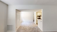 Located at 3 Rosemary Way in Reisterstown, Maryland, this single-floor residence offers a clean, neutral aesthetic throughout its well-organized layout. The living area is generously proportioned, finished with soft wall-to-wall carpeting in a warm neutral tone and crisp white walls that create a bright, welcoming atmosphere. A wide open archway connects the living space to the kitchen, promoting an open, airy feel between the two areas.

The kitchen is thoughtfully appointed with light gray cabinetry, sleek stone-look countertops, and stainless steel appliances including an electric range and dishwasher. An under-cabinet range hood adds a practical finishing touch, while the overall design balances functionality with a contemporary aesthetic.

The bedrooms are carpeted and generously sized, each featuring windows that invite natural light and offer views of the surrounding greenery. One bedroom includes two six-panel doors, providing access to a closet and an adjoining space, adding to the room's versatility. The bathroom is finished with wood-look flooring, a tiled tub-shower combination, a white vanity with an integrated sink, and updated brushed nickel fixtures. Throughout the residence, six-panel interior doors and neutral tones contribute to a cohesive, understated design.