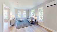 Located at 3624 N Conrad St in Philadelphia, this single-floor unit showcases a clean, modern design with consistent light hardwood flooring and neutral tones throughout. The living area is bright and welcoming, framed by multiple large windows that offer views of surrounding greenery, flooding the space with natural light. The open layout connects seamlessly to the kitchen, which features a striking two-tone design with navy lower cabinets, light wood upper cabinetry, white quartz countertops, a subway tile backsplash, and a full suite of stainless steel appliances. A peninsula with seating provides additional prep space and casual dining. The bedrooms are well-proportioned with large windows, recessed lighting, and ductless mini-split systems for climate control. The bathroom is finished in a contemporary style with dark tile flooring, a modern vanity with a framed mirror, and a glass-enclosed walk-in shower. A dedicated laundry area houses a stacked full-size washer and dryer alongside a water heater, adding practical convenience. The overall ambiance is fresh, minimalist, and move-in ready.