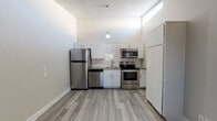 Located at 13517 W Glendale Ave in Glendale, Arizona, this single-story unit offers a practical and efficiently designed layout with one bedroom and one bathroom. The kitchen is a standout feature, boasting white shaker cabinetry, a classic subway tile backsplash, grey countertops, and a full suite of stainless steel appliances including a refrigerator, electric range, microwave, and dishwasher. A pendant light fixture and a high clerestory window add brightness and visual interest to the kitchen space. Throughout the unit, durable wood-look vinyl plank flooring provides a clean, cohesive aesthetic. The living area is open and airy, featuring a wall-mounted air conditioning unit and a window with blinds that allows natural light to fill the room. The bedroom is a comfortable, neutral-toned space with a ceiling fan and easy access to additional areas of the unit. The bathroom is well-appointed with a full tub and shower combination featuring tiled surround, a modern floating vanity with a white basin sink, and a framed mirror with accent lighting. Textured ceilings are present throughout, adding a subtle architectural detail to this move-in ready unit.