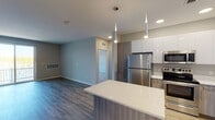 This contemporary single-floor residence offers a well-designed open-concept layout with clean lines and modern finishes throughout. The kitchen is a standout feature, equipped with stainless steel appliances including a refrigerator, range, microwave, and dishwasher. High-gloss white upper cabinetry contrasts elegantly with wood-toned lower cabinets, all topped with crisp white quartz countertops. A central island with a matching quartz surface provides additional prep space and informal seating, while pendant lighting adds a refined touch overhead. Recessed lighting and light wood-style flooring complete the kitchen and living area, creating a bright, cohesive atmosphere. The living space opens to a private balcony through a sliding glass door, allowing natural light to pour in.

The bedrooms are carpeted for comfort and feature neutral toned walls, with windows offering scenic views of a nearby body of water and surrounding greenery. The bathrooms are finished with modern wood-grain vanities, white quartz countertops, undermount sinks, large mirrors with vanity lighting, and tiled shower areas. The primary bathroom includes a dual-sink vanity and a spacious tiled shower. Throughout the unit, the design maintains a consistent, neutral palette that feels clean, calm, and move-in ready.