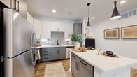 Located at 701 Saginaw Blvd in Saginaw, TX, this thoughtfully designed one-bedroom, one-bathroom residence offers a comfortable and modern living experience across a single floor. The open-concept layout seamlessly connects the kitchen, dining, and living areas, creating an efficient and inviting atmosphere throughout.

The kitchen is a standout feature, showcasing two-tone cabinetry with white upper cabinets and gray lower cabinets, complemented by matte black hardware, a textured tile backsplash, quartz countertops, and stainless steel appliances. A kitchen island with seating provides additional prep space and casual dining. Stylish pendant lighting enhances the modern aesthetic.

The living room is bright and welcoming, with a sliding glass door that invites natural light and provides direct access to the private patio. A ceiling fan adds comfort, and the space flows naturally into the dining area. The patio overlooks a landscaped community setting enclosed by a classic iron fence.

The bedroom is a serene retreat, featuring a window with natural light, wood-look flooring, and a dedicated closet. The bathroom is finished with large-format wall tile and includes a soaking tub. Wood-look flooring runs throughout the main living areas, tying the design together with a warm, cohesive feel.