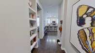 This single-floor, 2-bedroom, 2-bathroom residence offers a clean, modern aesthetic with consistent design details throughout. The entryway sets the tone with built-in open shelving and dark hardwood-style flooring that carries through the main living areas. The open-concept kitchen and living room form the heart of the home, where the kitchen features white shaker cabinetry, granite countertops, a tile backsplash, stainless steel appliances including a French door refrigerator, and a breakfast bar with bar seating. The living room benefits from an abundance of natural light streaming through multiple large windows, creating a bright and welcoming atmosphere. Both bathrooms are finished with granite vanity countertops, white cabinetry, large-format tile surrounds in the tub-shower combinations, and dark hardwood-style flooring. The bedrooms feature plush carpeting and generously sized windows that invite natural light. The primary bedroom is a comfortable retreat with a well-organized walk-in closet offering built-in shelving and double hanging rods. Two hallways and additional closets provide practical storage solutions throughout. The space combines modern finishes with functional design, making for an efficient and stylish layout.