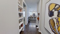 This single-floor, 2-bedroom, 2-bathroom residence offers a clean, modern aesthetic with consistent design details throughout. The entryway sets the tone with built-in open shelving and dark hardwood-style flooring that carries through the main living areas. The open-concept kitchen and living room form the heart of the home, where the kitchen features white shaker cabinetry, granite countertops, a tile backsplash, stainless steel appliances including a French door refrigerator, and a breakfast bar with bar seating. The living room benefits from an abundance of natural light streaming through multiple large windows, creating a bright and welcoming atmosphere. Both bathrooms are finished with granite vanity countertops, white cabinetry, large-format tile surrounds in the tub-shower combinations, and dark hardwood-style flooring. The bedrooms feature plush carpeting and generously sized windows that invite natural light. The primary bedroom is a comfortable retreat with a well-organized walk-in closet offering built-in shelving and double hanging rods. Two hallways and additional closets provide practical storage solutions throughout. The space combines modern finishes with functional design, making for an efficient and stylish layout.