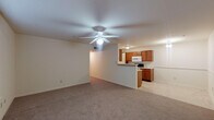 This single-floor residence offers a practical and cohesive layout designed for comfortable everyday living. The living area is generously sized, featuring neutral-toned carpet, a ceiling fan with integrated lighting, and a window fitted with blinds that allows natural light to fill the space. A chair rail detail lines the walls, adding a subtle architectural accent. The entryway opens directly into this main living space, reinforcing the open feel of the floor plan.

The kitchen is positioned adjacent to the living area and separated by a half-wall breakfast bar. Warm medium-toned wood cabinetry lines the walls, complemented by light countertops and tile flooring. White appliances, including a refrigerator, electric range, and over-the-range microwave, provide a clean, cohesive look throughout the galley-style space.

Both bedrooms are carpeted and equipped with ceiling fans and natural light from windows with blinds. One bedroom includes access to a spacious walk-in closet outfitted with wire shelving on multiple walls, offering ample storage capacity.

Two full bathrooms serve the unit, each featuring matching wood cabinetry, a single-sink vanity, a tub-shower combination, and light tile flooring, maintaining a consistent design throughout.