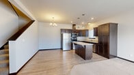 This two-story home in Rochester, MN offers a well-designed layout spread across two floors. The main level features an open-concept living and kitchen area with light wood-look flooring that flows seamlessly throughout. The kitchen is a standout, showcasing rich dark espresso cabinetry, granite countertops, a central island with bar seating, stainless steel appliances including a refrigerator, range, microwave, and dishwasher, and stylish pendant lighting. A convenient half bathroom on the main level features a pedestal sink and wood-framed mirror, ideal for guests. A staircase with a dark wood handrail leads to the upper floor. Upstairs, two carpeted bedrooms offer comfortable retreats, with the primary bedroom benefiting from dual windows that invite natural light and provide views of the surrounding neighborhood. The upper level also includes two full bathrooms, one featuring a soaking tub/shower combo with hexagon tile flooring, as well as a dedicated laundry room complete with a full-size washer and dryer and overhead shelving. A hallway closet provides additional storage. The home's clean, neutral palette and consistent dark trim details create a cohesive and modern aesthetic throughout.