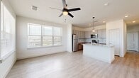 This single-floor residence offers a thoughtfully designed open-concept layout encompassing two bedrooms, two bathrooms, a kitchen, living room, laundry room, and a closet. Light-toned luxury vinyl plank flooring flows throughout the main living areas, complemented by neutral wall tones that create a bright, airy atmosphere throughout.

The kitchen serves as a functional centerpiece, featuring granite countertops, a large island with an undermount sink, gray shaker-style upper cabinetry, warm wood-toned lower cabinets, a subway tile backsplash, and a full suite of stainless steel appliances including a refrigerator, range, and microwave. Pendant lighting and an adjacent large window flood the space with natural light and outdoor views.

The open living area is anchored by a ceiling fan with light fixture and a wide window offering additional outdoor views, creating a comfortable and well-lit gathering space.

The bedrooms are carpeted for comfort, each featuring windows with blinds that bring in natural light. The bathrooms are finished with granite-topped vanities, gray cabinetry with brushed nickel hardware, and a bathtub-shower combination. A dedicated laundry room houses a full-size washer and dryer with overhead wire shelving. An electrical panel is conveniently recessed into the hallway wall.
