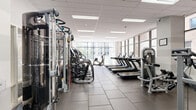 Located at 210 N Wells St in the heart of Chicago's Loop, this well-appointed fitness center spans a generously sized single floor divided into two dedicated exercise rooms. The facility is designed to support a full spectrum of workout routines, from cardiovascular training to strength and functional fitness.

The primary exercise room is flooded with natural light through expansive floor-to-ceiling windows that frame views of the surrounding Chicago skyline. This bright, open space houses a robust lineup of cardio equipment, including multiple treadmills, ellipticals, and stair climbers, all arranged along the windowed perimeter for an energizing workout environment. A dedicated strength training zone features Matrix cable machines, cable crossover stations, plate-loaded equipment, free weights, and adjustable benches, providing a comprehensive selection for resistance training.

The secondary exercise room offers a more intimate setting with a horizontally striped accent wall and rubber flooring, designed for functional and cross-training activities. It is equipped with a rowing machine, spin bike, medicine balls, a punching bag, and a foldable weight bench, making it ideal for high-intensity or circuit-style workouts.

Throughout both rooms, durable rubber tile flooring, recessed panel ceilings with flush LED lighting, and wall-mounted televisions contribute to a clean, modern aesthetic. The facility's thoughtful layout and extensive equipment selection make it a versatile training destination in the heart of Chicago.