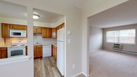 This single-floor residence at Harrington Gardens offers a well-organized layout designed for comfortable everyday living. The kitchen is a standout feature, equipped with warm honey-toned oak cabinetry providing generous storage, white appliances including a range, built-in microwave, dishwasher, and refrigerator, complemented by light countertops and durable wood-look flooring. The kitchen opens conveniently toward the living areas, creating a connected feel throughout the space.

The living and dining areas are carpeted in neutral tones, offering a clean, understated aesthetic. Windows fitted with blinds allow natural light to filter in while providing views of the surrounding exterior. Wall-unit climate control and baseboard heating are present, ensuring year-round comfort. Ceiling fans in select rooms add to the practical design.

The bedrooms are generously proportioned, featuring plush carpeting and ample closet space, including a walk-in closet in the primary bedroom. The bathroom includes a full-size soaking tub with a tiled shower surround and tile flooring. Throughout the residence, neutral wall tones and white trim create a cohesive, move-in-ready atmosphere.