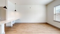 Located in Bixby, Oklahoma, this single-floor unit offers a thoughtfully designed layout that maximizes every square foot. Light wood-look flooring flows throughout, unifying the space with a warm, contemporary feel. The open-concept kitchen and living area serves as the heart of the unit, where the kitchen stands out with slate-gray shaker cabinets, a white subway tile backsplash, stainless steel appliances — including a refrigerator, range, and dishwasher — and a central island with a crisp white countertop that doubles as additional prep and dining space. Pendant lighting accents the island, adding a stylish touch. The living area is bright and airy, with multiple windows dressed in horizontal blinds that invite natural light while maintaining privacy. A modern ceiling fan with wood-toned blades enhances comfort and airflow. The bathroom is finished to a high standard, featuring marble-look tile in the walk-in shower, mosaic tile flooring, and stainless steel grab bars that provide both accessibility and a sleek aesthetic. The dedicated laundry room includes a full-size front-loading washer and dryer set alongside built-in shelving for storage, adding exceptional everyday convenience to this well-rounded unit.