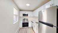 This thoughtfully designed one-bedroom, one-bathroom unit offers a clean, modern aesthetic across its single floor. Light wood-style flooring runs throughout the main living areas, complementing the neutral gray-toned walls and bright white trim that create a cohesive and airy feel.

The living room is a comfortable and well-lit space, featuring recessed lighting, a wall-mounted HVAC unit, and a baseboard heating system. Natural light filters in through a window, adding warmth to the open layout. The space connects seamlessly to a dedicated entryway with a closet and a utility panel.

The kitchen is a standout feature, outfitted with crisp white shaker-style cabinetry, light quartz countertops, a subway tile backsplash, and a full suite of stainless steel appliances including a range, over-the-range microwave, dishwasher, and refrigerator. A window provides additional natural light, enhancing the kitchen's bright, clean atmosphere.

The bedroom is a generously sized private retreat with a double closet, recessed and flush-mount lighting, and the same light wood flooring found throughout the unit.

The bathroom features large-format dark tile flooring, a white vanity with a mirror, and brushed nickel fixtures, offering a polished, contemporary finish. Overall, the unit presents a fresh, move-in-ready space with consistent modern detailing throughout.
