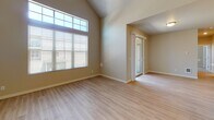 This single-floor residence offers a thoughtfully designed layout with a blend of practical features and inviting finishes throughout. The living area is highlighted by vaulted ceilings and large windows, including transom windows that draw in abundant natural light. Light-toned hardwood-style flooring flows through the main living space, adding warmth and continuity. A sliding glass door connects the living area to a private balcony with a railed enclosure, offering views of the surrounding neighborhood.

The kitchen is well-equipped with dark espresso cabinetry extending to the ceiling, stainless steel appliances including a refrigerator, electric range, and built-in microwave, and clean white countertops that provide a striking contrast to the cabinetry.

The bedrooms are carpeted for comfort. One bedroom features tall windows with transom panels that maximize natural light, while another includes a walk-in closet fitted with wire shelving systems for organized storage. The bathroom is clean and functional, featuring a full soaking tub with a shower, wood-look vinyl flooring, dark vanity cabinetry, and chrome towel hardware, all set beneath a vaulted ceiling that adds an airy quality to the space.