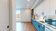 Located at 1309 in Boston, MA 02134, this thoughtfully designed studio offers a well-utilized single-floor layout that combines the kitchen and living area into one cohesive, open space. Warm hardwood-style flooring runs throughout the main living area, complementing the clean white walls and recessed lighting that keep the space feeling bright and airy. Oversized floor-to-ceiling windows invite abundant natural light and provide open views of the surrounding Boston neighborhood, enhancing the sense of space.

The kitchen is a standout feature, showcasing two-tone cabinetry with slate-blue lower cabinets and crisp white uppers, all accented by matte black hardware. A white subway tile backsplash, stainless steel appliances including a dishwasher and microwave, and a deep sink round out this modern, functional kitchen. An in-unit washer and dryer are neatly tucked away, adding everyday convenience.

The bathroom is finished to a high standard, featuring large-format floor tiles, a walk-in shower with white stacked mosaic tile surround, a curved shower rod, and sleek matte black fixtures throughout. A floating vanity with a wood-toned base and a well-placed mirror complete the polished look. The overall ambiance of the studio is modern, clean, and efficiently designed for comfortable urban living.